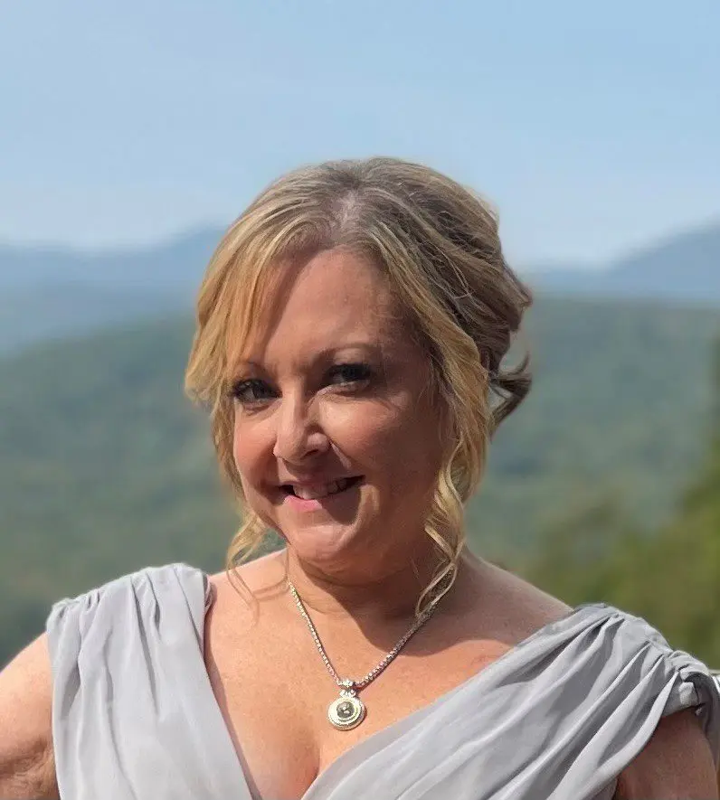 Woman in gray dress smiling with necklace.