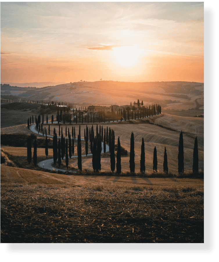 Sunset over Tuscan countryside with trees.